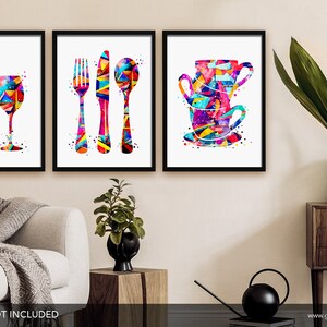 May include: Set of three colorful abstract watercolor prints featuring a wine bottle and glass, a fork, knife, and spoon, and a stack of teacups. The prints are framed in black frames.