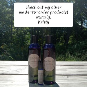 May include: Two dark blue bottles and a small roller bottle of SolSoma brand oil are displayed on a wooden surface. The bottles have white labels with text. A sign above reads "check out my other made-to-order products! warmly, Kristy."