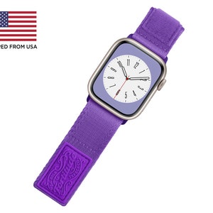 Może przedstawiać: Fioletowy pasek do Apple Watch z białą tarczą zegarka i logo "Fortitude" na pasku.