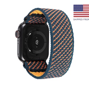 May include: A black Apple Watch with a blue, orange and yellow woven sport band. The watch face is black and shows the time and date.