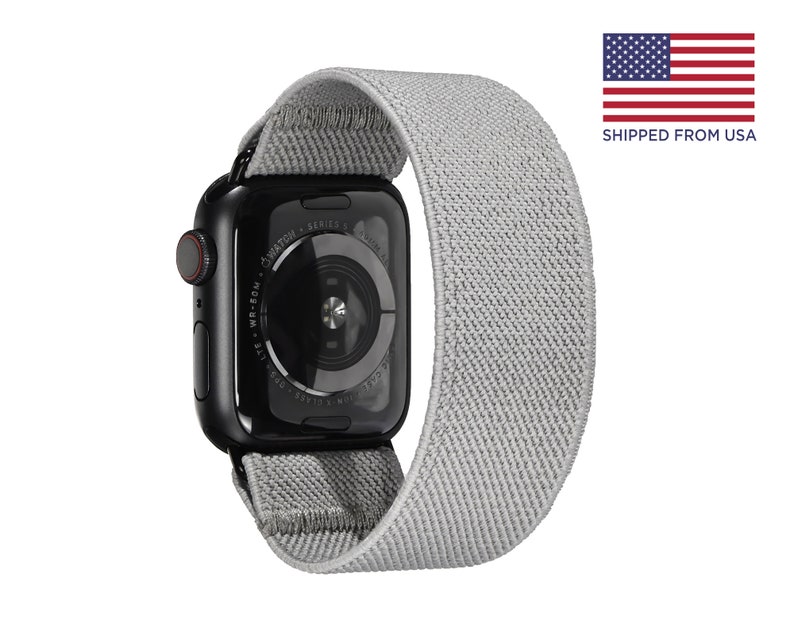May include: A black Apple Watch Series 6 with a gray sport loop band. The watch face is black with white text that reads "WATCH - SERIES 6 - APPLE - WR-50M -  ION-X GLASS -  APPLE WATCH"