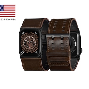 May include: A brown leather watch band with a black metal buckle and a black Apple Watch with a world time watch face.