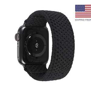 May include: Black Apple Watch with a black sport loop band. The watch face is a digital display with a black background and white numbers. The band is made of a breathable, stretchy material.