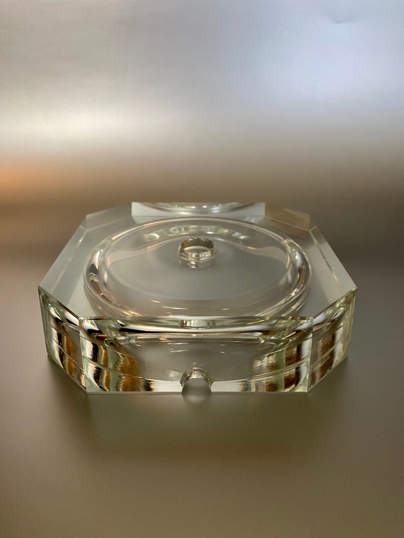 May include: A clear glass octagonal base with a round center hole. The base is designed to hold a candle or other decorative object.