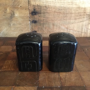 May include: A pair of black ceramic salt and pepper shakers with a textured design.