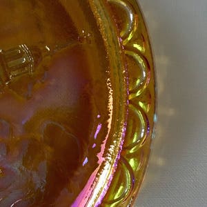 Peut inclure: Une assiette en verre jaune iridescent avec un bord festonn&eacute;. L'assiette a un motif en relief au centre.