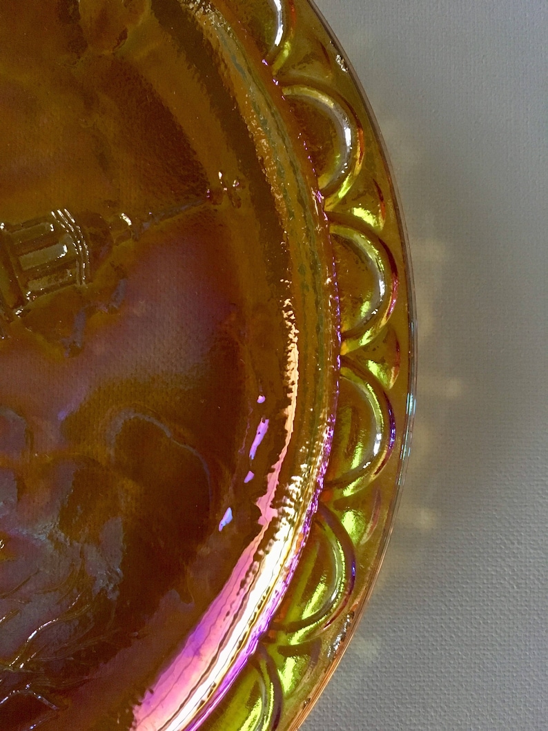 Peut inclure: Une assiette en verre jaune iridescent avec un bord festonn&eacute;. L'assiette a un motif en relief au centre.