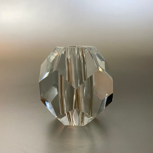 May include: A clear glass bead with a faceted design. The bead is round and has a smooth, polished surface.