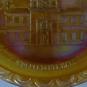 Peut inclure: Une assiette en verre ambr&eacute; vintage avec une image en relief de l'Independence Hall &agrave; Philadelphie, en Pennsylvanie. L'assiette a un bord festonn&eacute; et les mots "Independence Hall" sont inscrits autour du bas.