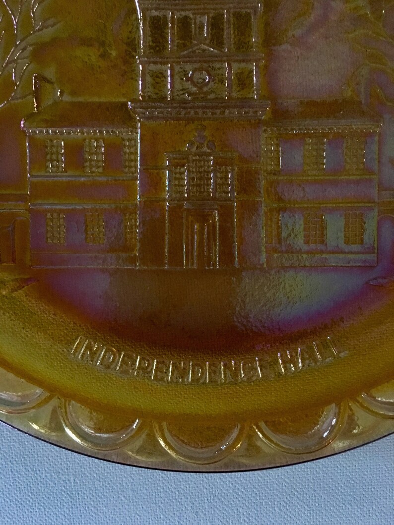 Peut inclure: Une assiette en verre ambr&eacute; vintage avec une image en relief de l'Independence Hall &agrave; Philadelphie, en Pennsylvanie. L'assiette a un bord festonn&eacute; et les mots "Independence Hall" sont inscrits autour du bas.