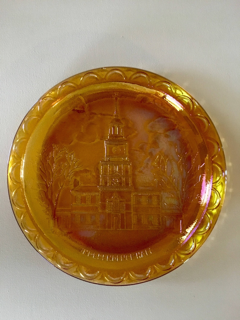 Peut inclure: Une assiette ronde en verre ambr&eacute; avec un bord festonn&eacute; sur&eacute;lev&eacute;. L'assiette pr&eacute;sente une image grav&eacute;e de l'Independence Hall &agrave; Philadelphie, en Pennsylvanie.
