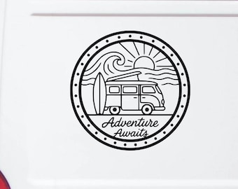 May include: A circular black and white vinyl decal applied to a white vehicle. The design features a camper van, a surfboard, ocean waves, and a sun, enclosed by a dotted border. The text Adventure Awaits is printed in a script font at the bottom.