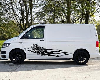 May include: A white van featuring a large black vinyl decal on the side panel. The graphic depicts a leaping tiger with its body transitioning into stylized flames that extend horizontally toward the rear of the vehicle, creating a dynamic look.