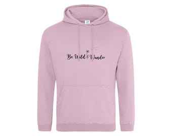 May include: A light mauve hooded sweatshirt featuring a front kangaroo pocket, long sleeves, and a drawstring hood. The chest displays a black graphic of a dandelion with seeds blowing in the wind and the text Be Wild & Wander.