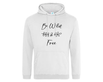 May include: A white hooded sweatshirt featuring long sleeves, a front kangaroo pocket, and a drawstring hood. The chest displays the black text "Be Wild & Free" with a decorative line of small leaf-like flourishes between the words.