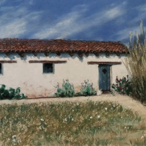 May include: A white adobe building with a red tile roof, two windows, and a blue door. The building is surrounded by green grass and tall, dry grass.