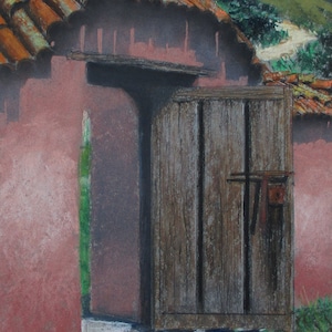 May include: A weathered wooden door with a rusty metal latch is partially open, revealing a glimpse of a red brick wall and a green plant. The door is set against a backdrop of a terracotta tiled roof and a lush green hillside.