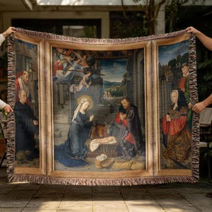 May include: A woven tapestry throw blanket featuring a triptych-style religious nativity scene. The central panel depicts the Holy Family with an ox and angels, while the side panels show figures in historical attire. The blanket has a fringed edge.