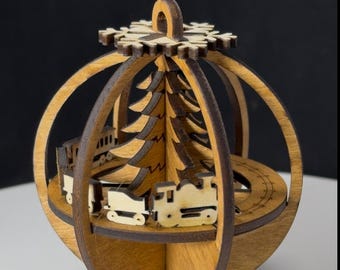 May include: Wooden Christmas ornament shaped like a sphere, featuring a laser-cut train circling a Christmas tree. The ornament has a snowflake design at the top and is made of light and dark brown wood. The train has several cars.
