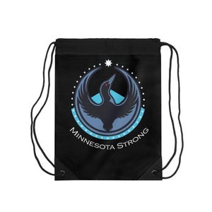 May include: Black drawstring bag featuring a circular emblem with a stylized bird in shades of blue and a red eye. The emblem is surrounded by a dotted border and the words "Minnesota Strong". The bag has black drawstrings.