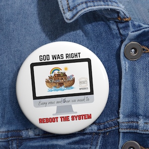 Op de afbeelding: Witte knoop met de tekst "GOD WAS RIGHT" bovenaan en "REBOOT THE SYSTEM" onderaan. De knoop toont een computerscherm met een afbeelding van de Ark van Noach, een regenboog en de woorden "RESET" en "INPROGRESS".