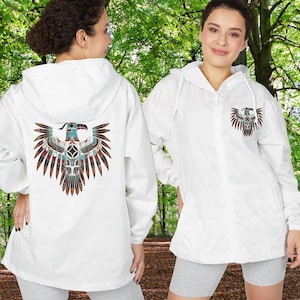 May include: White hooded jacket featuring a Native American-inspired eagle design on the back and chest. The eagle design incorporates shades of blue, brown, and red. The jacket has a zipper closure and a drawstring hood.