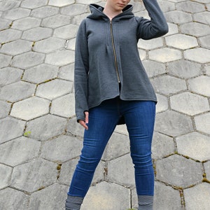 Pode incluir: Uma jaqueta de moletom cinza com capuz e fecho de z&iacute;per. A modelo est&aacute; usando jeans azul e meias cinzas com botas pretas.