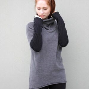 K&ouml;nnte beinhalten: Ein grauer Pullover mit Rollkragen und schwarzen &Auml;rmeln. Der Pullover ist aus weichem, bequemem Material und hat eine lockere Passform.