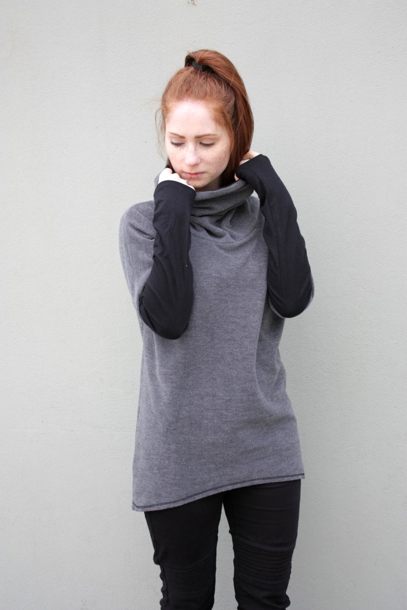 K&ouml;nnte beinhalten: Ein grauer Pullover mit Rollkragen und schwarzen &Auml;rmeln. Der Pullover ist aus weichem, bequemem Material und hat eine lockere Passform.