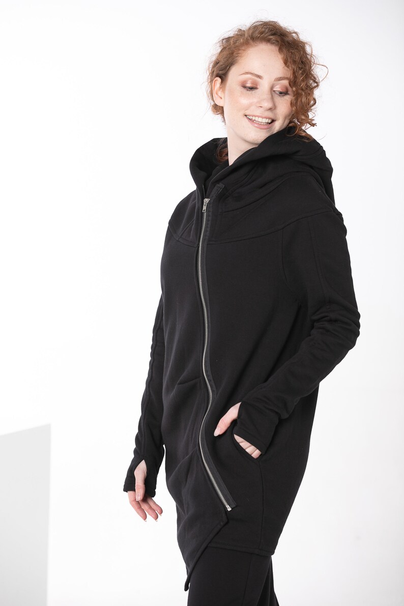 May include: A black hooded zip-up jacket with a long asymmetrical hemline and thumbholes.