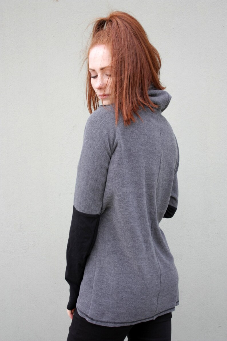 K&ouml;nnte beinhalten: Ein lang&auml;rmliges Shirt in Grau und Schwarz mit einem Rollkragen. Das Shirt hat einen schwarzen Einsatz an den Unterarmen.