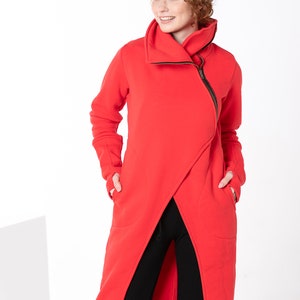 May include: A long red hooded sweatshirt with a zipper and pockets. The sweatshirt has a long, asymmetrical hemline.
