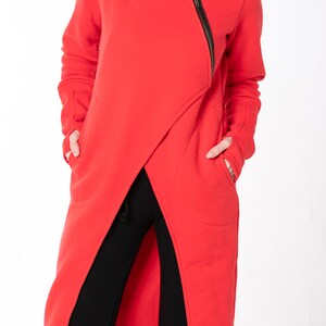 May include: A long red asymmetrical zippered sweatshirt with a high collar and two pockets.