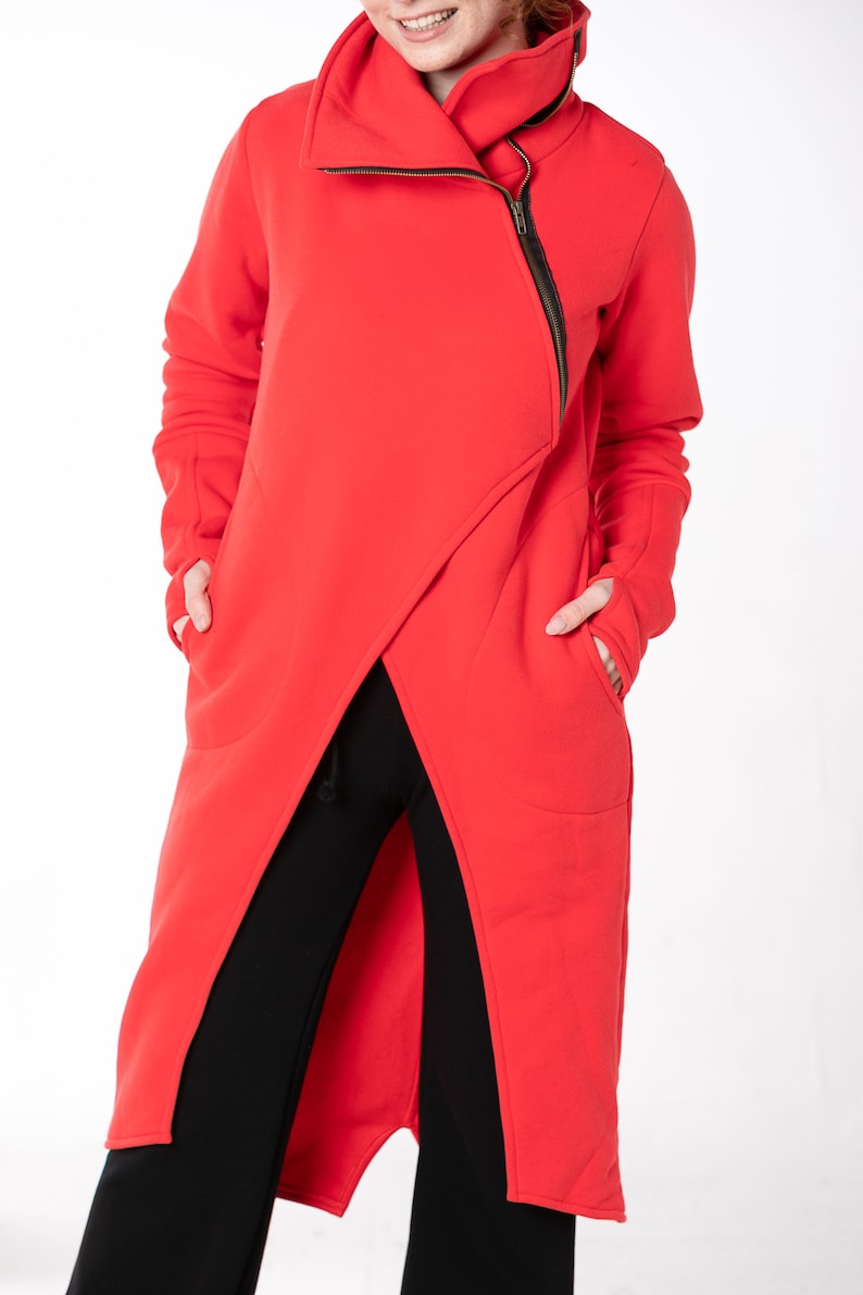 May include: A long red asymmetrical zippered sweatshirt with a high collar and two pockets.