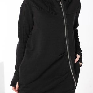 May include: Black hooded sweatshirt with a long zipper down the front. The sweatshirt has a relaxed fit and a slightly asymmetrical hem.