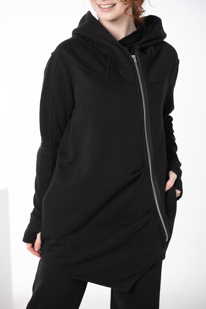 May include: Black hooded sweatshirt with a long zipper down the front. The sweatshirt has a relaxed fit and a slightly asymmetrical hem.