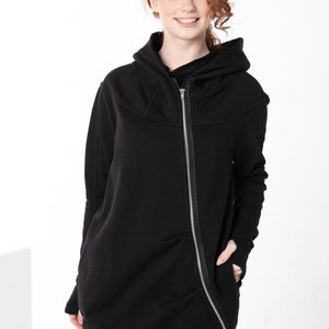 May include: A black hooded sweatshirt with a long zipper down the front and a slightly asymmetrical hem. The sweatshirt has a relaxed fit and a casual style.