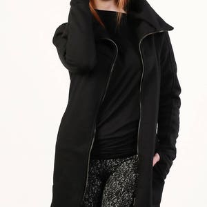 May include: A black long-sleeved jacket with a zipper closure and a high collar. The jacket has a relaxed fit and is made of a soft, comfortable fabric.