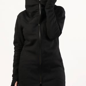 May include: A black long-sleeved jacket with a high collar and a zipper closure. The jacket has a relaxed fit and a slightly oversized look.