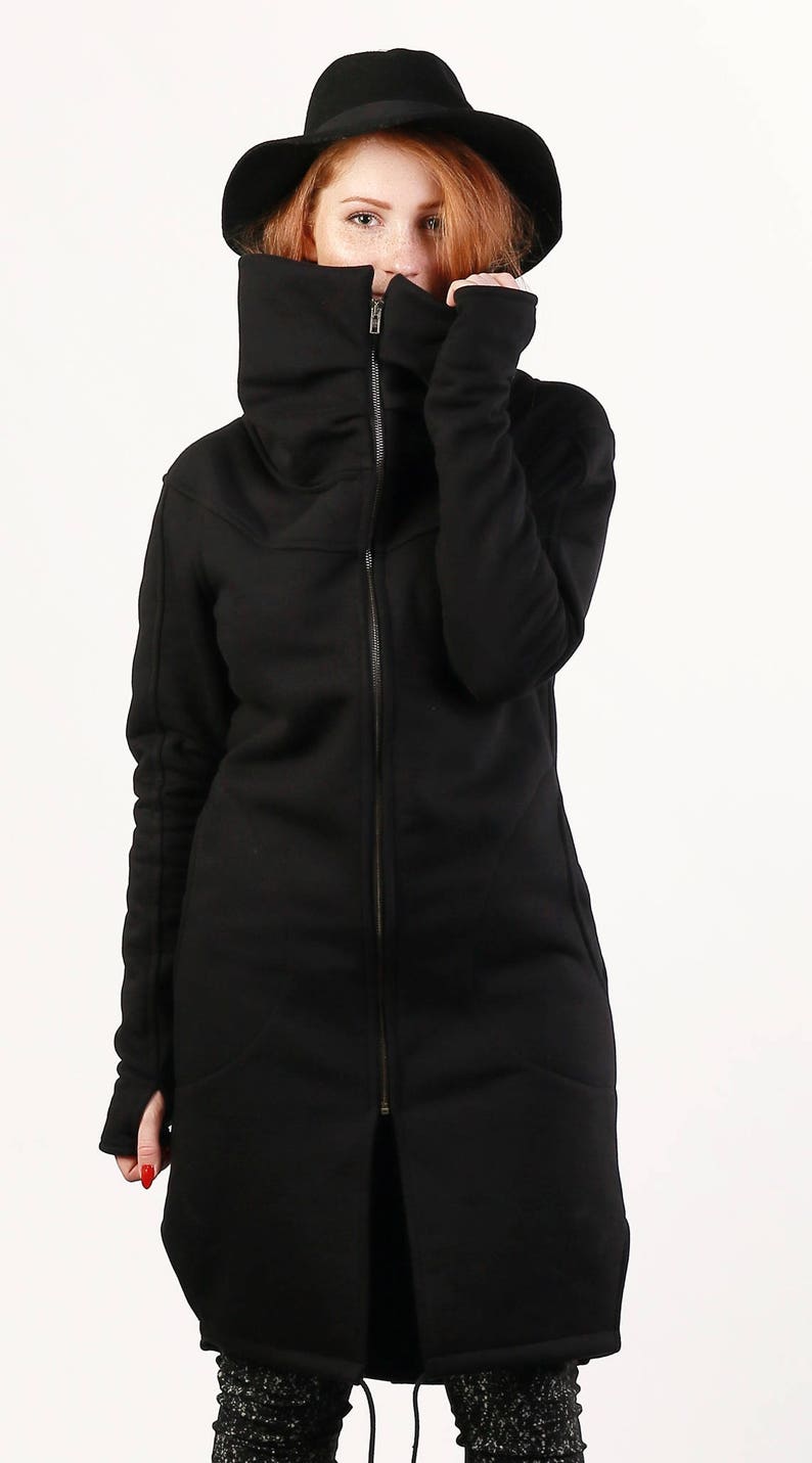 May include: A black long-sleeved jacket with a high collar and a zipper closure. The jacket has a relaxed fit and a slightly oversized look.