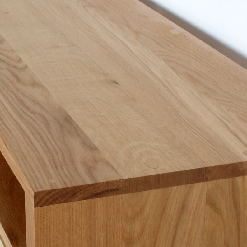 Puede incluir: Primer plano de la parte superior de un centro de entretenimiento de madera. La parte superior est&aacute; hecha de madera de color claro con un acabado liso.