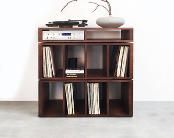 May include: A dark brown wooden record player stand with six shelves. The stand has a turntable on the top shelf and a stereo receiver on the shelf below. The stand is filled with vinyl records.