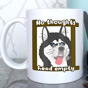 May include: White ceramic coffee mug with a brown border around a cartoon husky dog with the text "No thoughts head empty" printed on the mug.