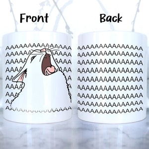 May include: White ceramic mug with a black and white illustration of a cat yelling "AAAAAAA" on the front. The back of the mug is covered in a repeating pattern of the word "AAAAAAA".