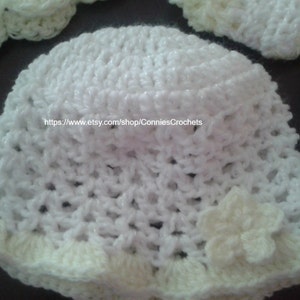 May include: White crocheted sun hat with a white flower accent. The hat has a wide brim and a crocheted band around the crown. The hat is made with a delicate, open stitch pattern. https://www.etsy.com/shop/ConniesCrochets