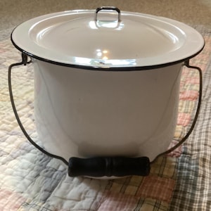 White enamelware chamber pot with black trim, lid and handle