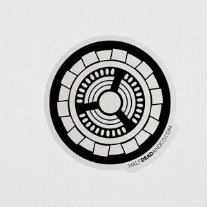 May include: Black and white circular design with concentric circles and a three-pointed star in the center. The design is surrounded by a ring of smaller circles. The text "HALF DEAD AND CO.COM" is printed around the outer edge of the circle.