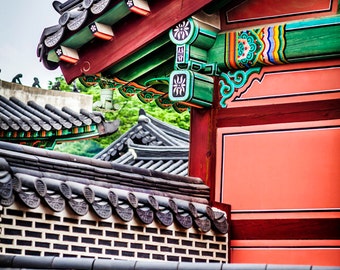 May include: A traditional Korean building with a red and green roof. The roof is decorated with intricate carvings and patterns. The building is made of wood and has a brick wall.