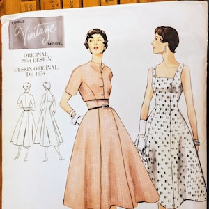 May include: Vintage Vogue sewing pattern for a dress, pattern number 2267, size 14. The pattern shows two women wearing different styles of dresses, one with a belt and the other with a sleeveless design. The text "Original 1954 Design" is printed on the pattern.