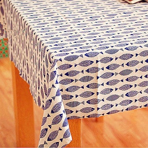 Könnte beinhalten: Eine weiße Tischdecke mit einem blauen Fischmuster. Die Tischdecke ist über einen Holztisch gelegt.